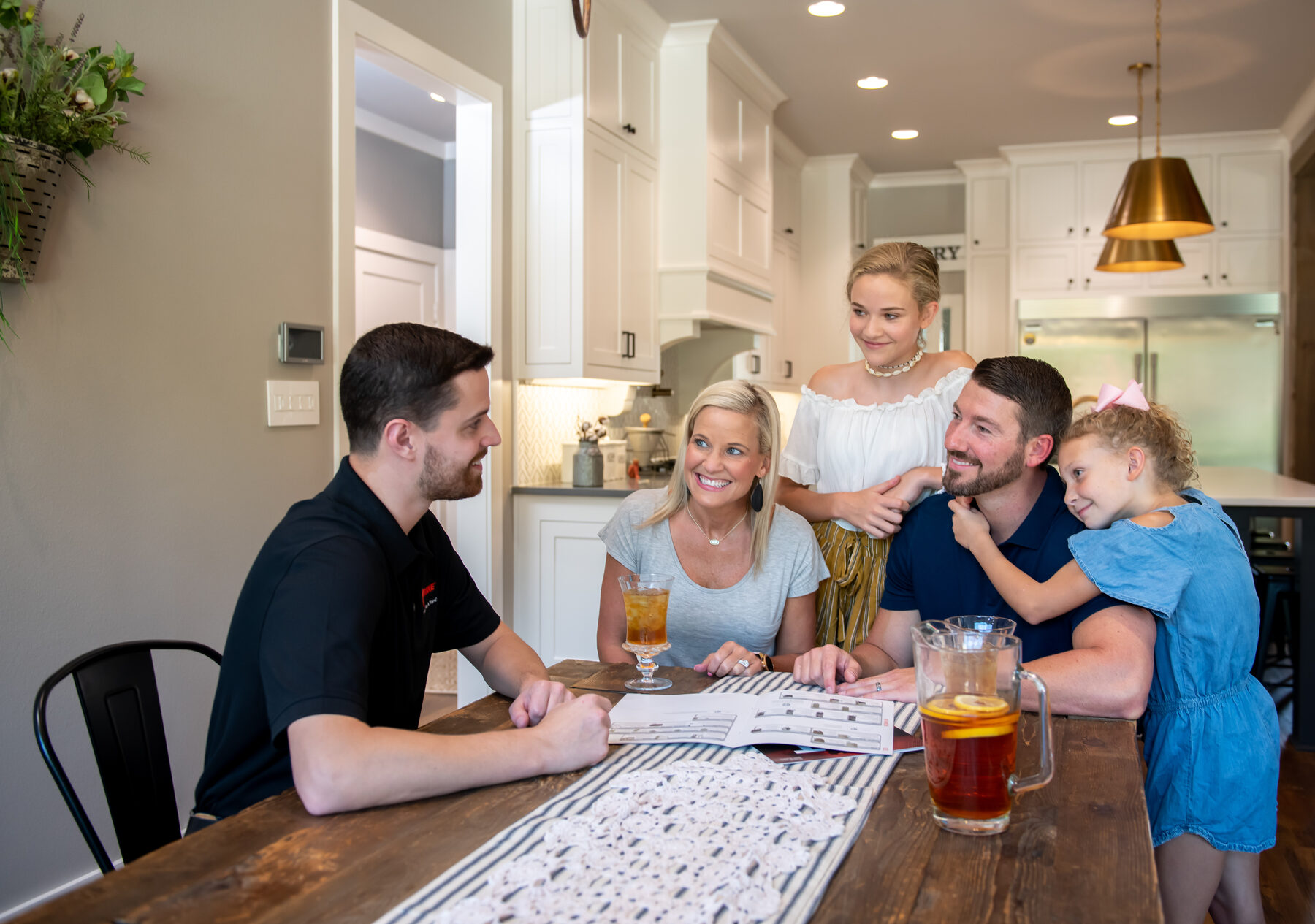 A homeowner reviewing a Pitch & Close pitch book at the kitchen table